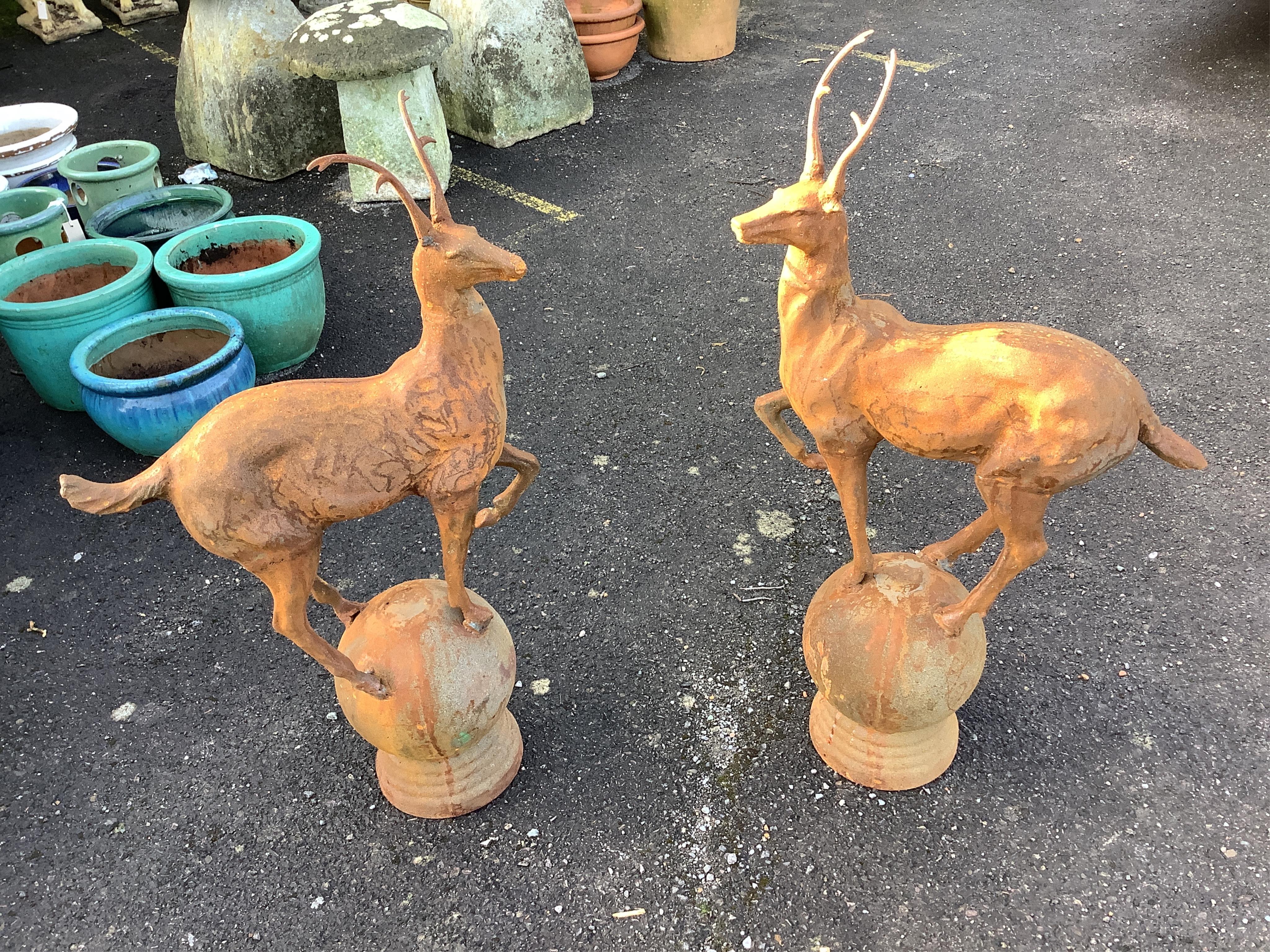 A pair of cast iron finials as deer standing upon spheres, height 92cm. Condition - weathered